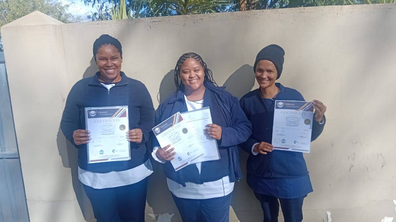 Three graduates holding certificates