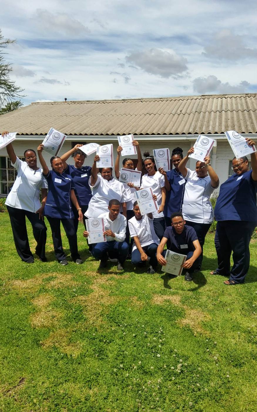 Graduating class holding certificates outdoors